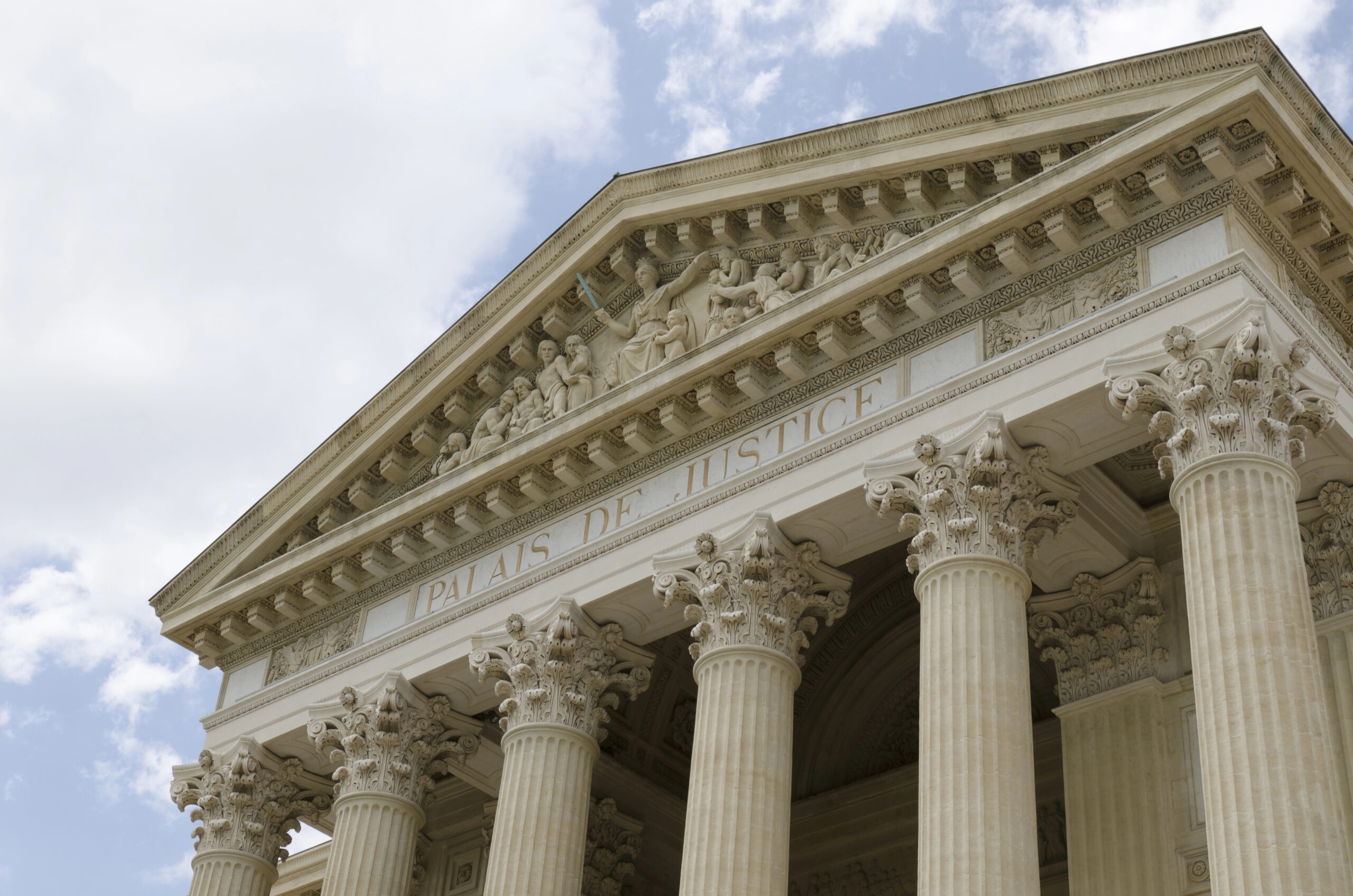 Front view of a courthouse, featuring tall columns and detailed relief above